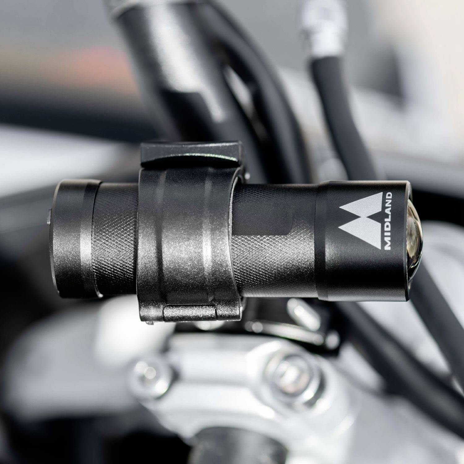 A black, cylindrical device in a mount, attached to a vehicle handlebar. The 'MIDLAND' logo is visible on it.