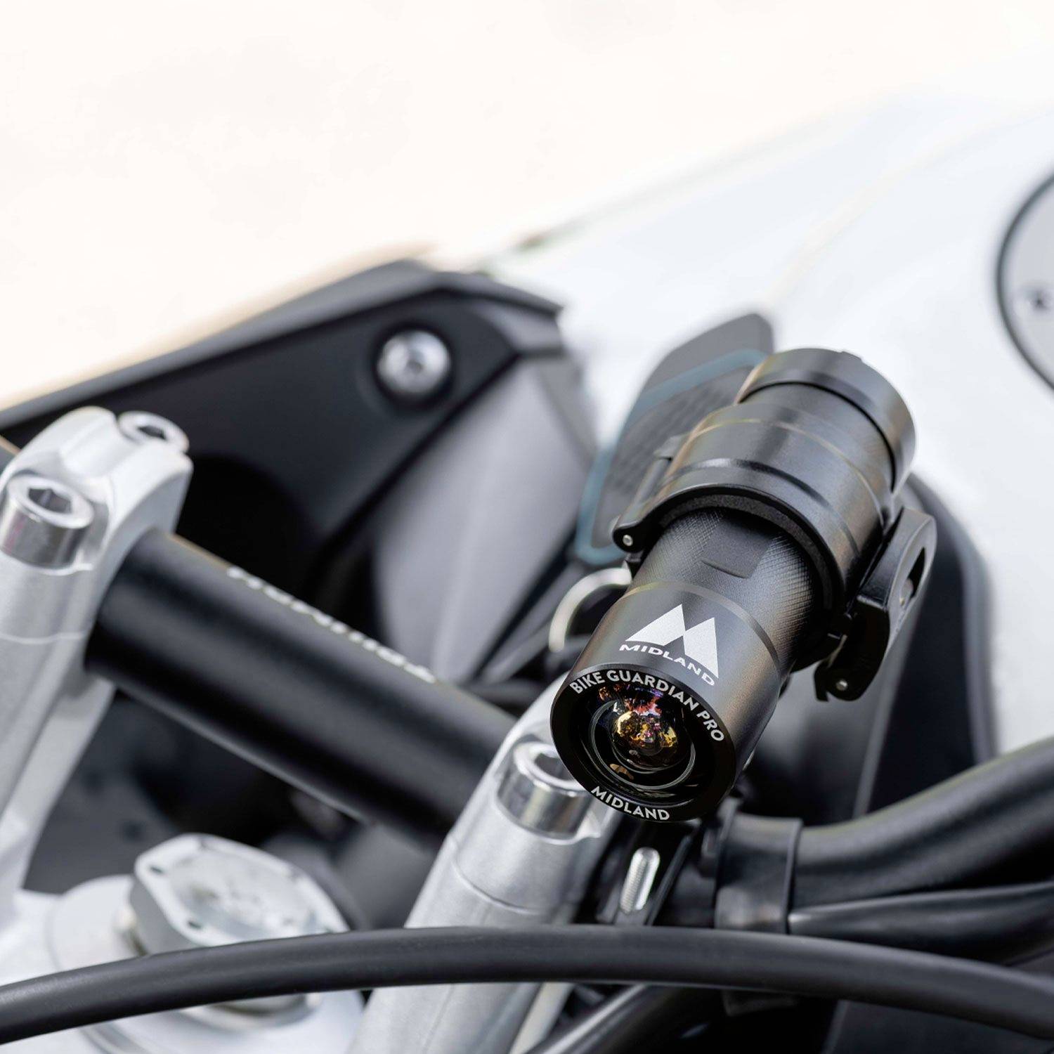 Close-up of a bicycle handlebar with a black action camera mounted. The camera is slightly angled to capture the forward view.