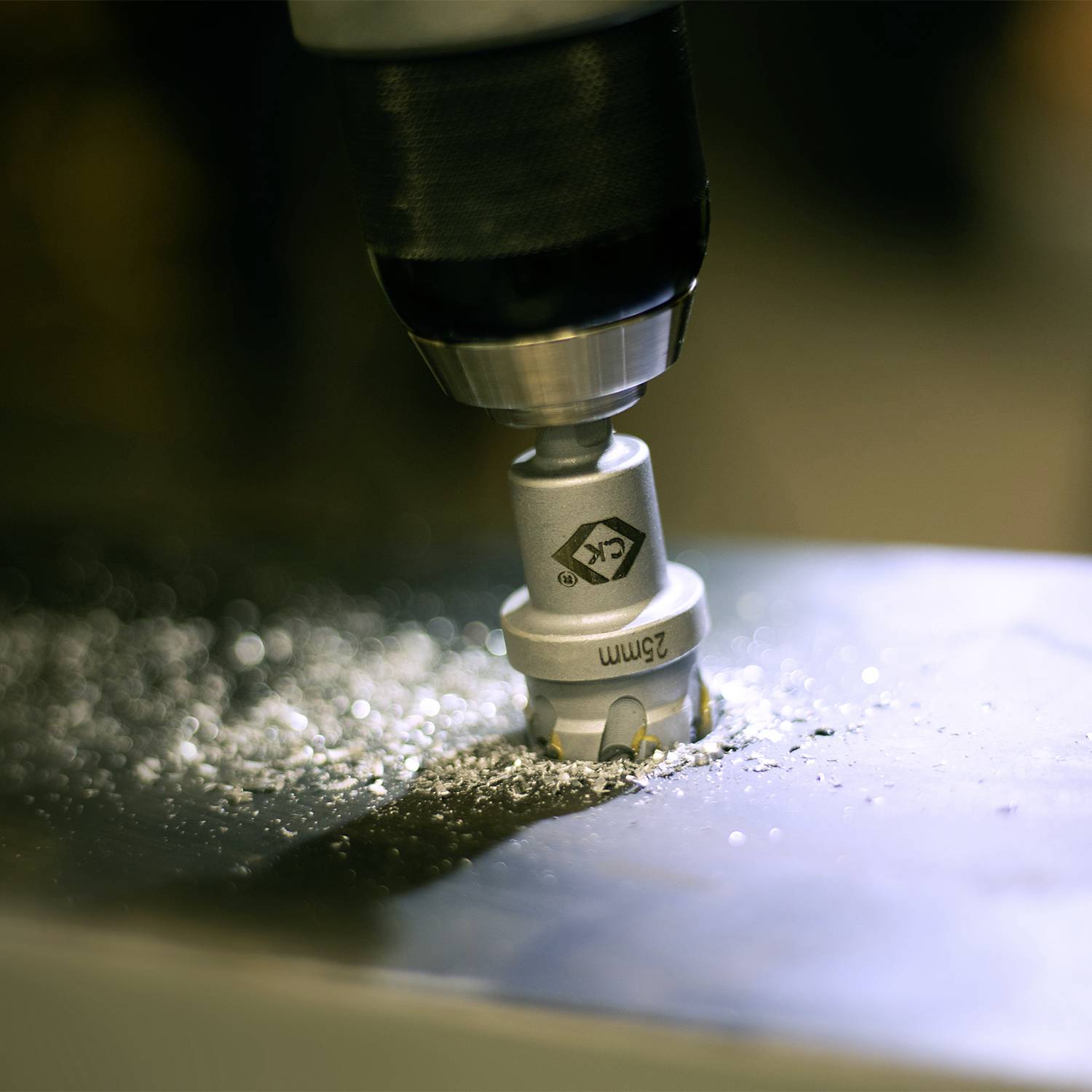 Drill pierces metal plate, metal shavings accumulate.