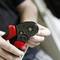 A person is using a red and black crimping tool to work on a cable. The scene shows a close-up of hands in action.