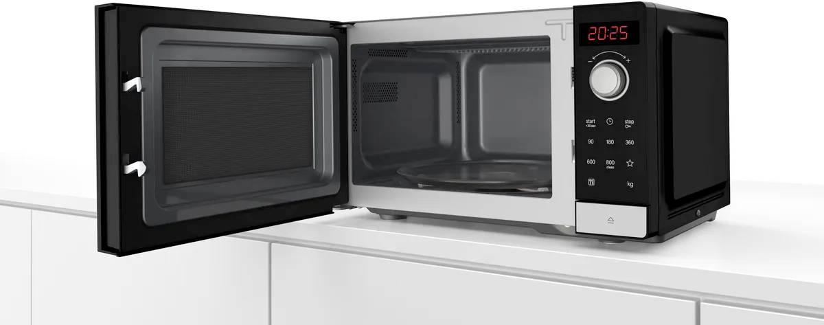 An open microwave is standing on a kitchen worktop. It displays the time '20:25' on a digital display.