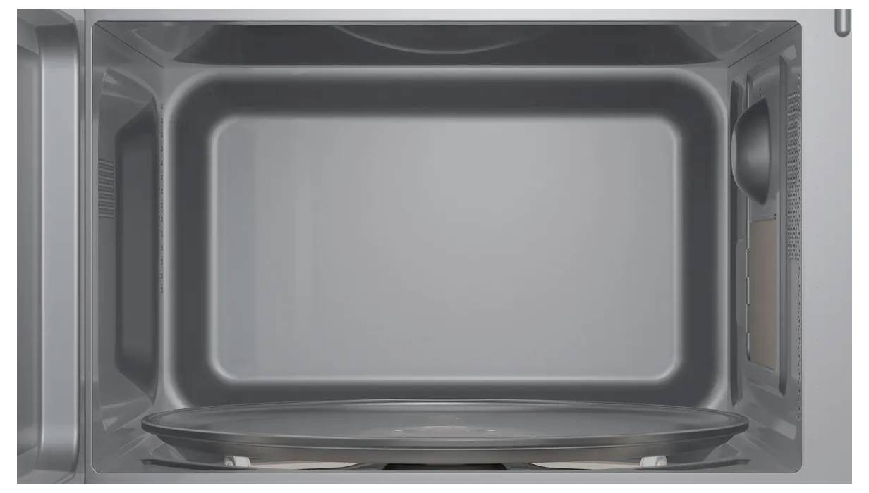 Interior view of a microwave with a turntable. Clearly visible, empty cooking chamber with grey walls and a smooth, metallic finish.