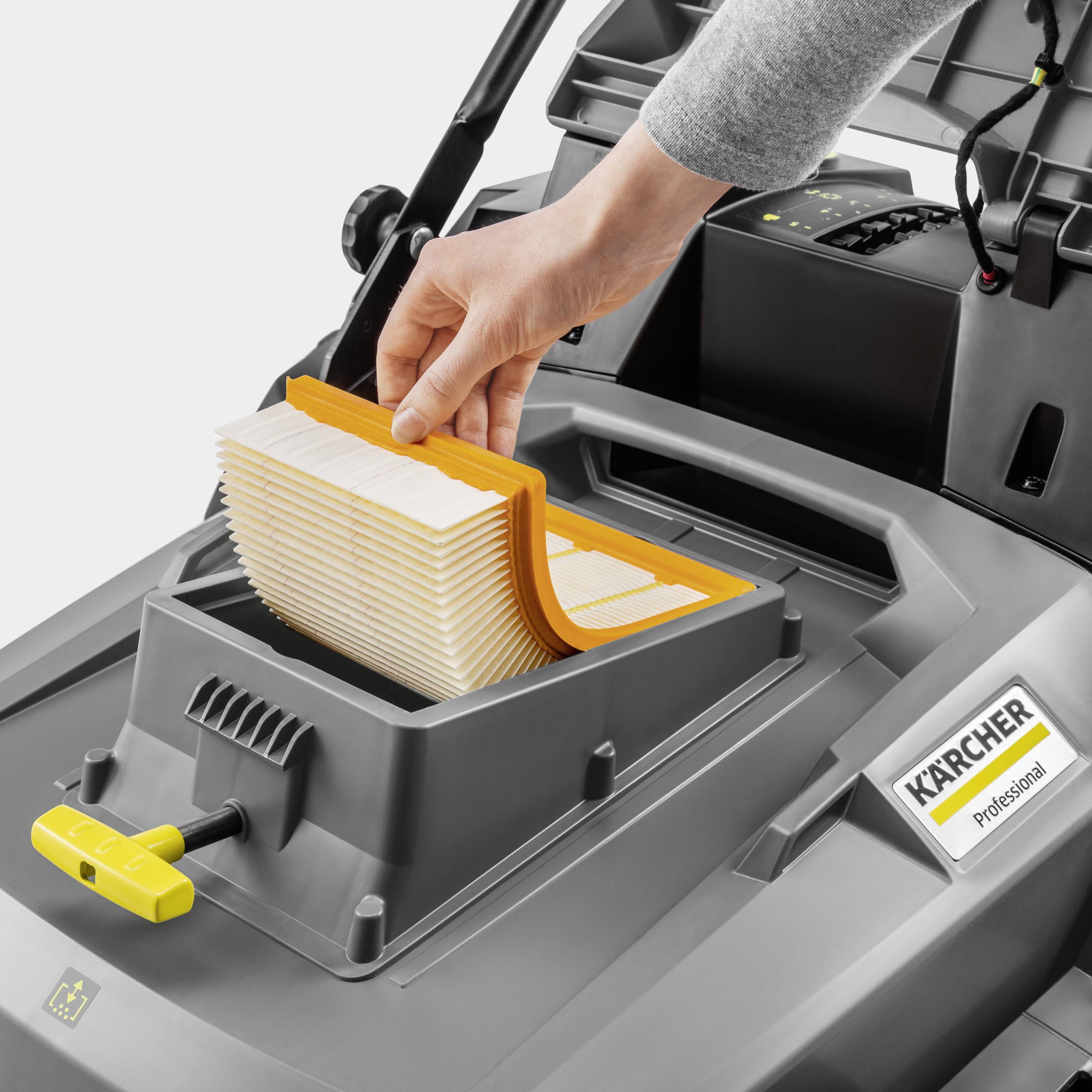 A hand is inserting a rectangular filter into a grey industrial vacuum cleaner, with the 'Kärcher Professional' logo beside it.