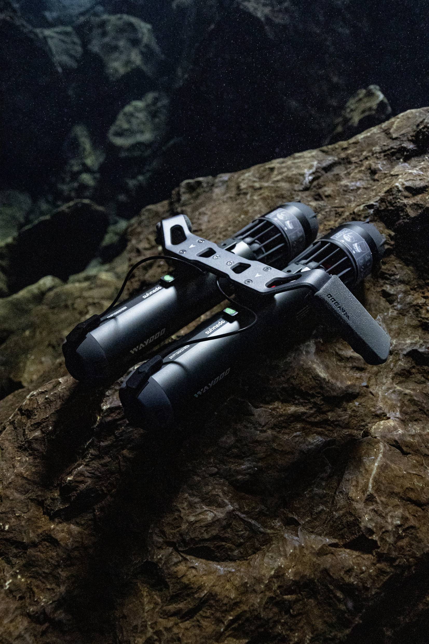 Underwater scooters are lying on a rock beneath the water, used for exploration or transportation in aquatic environments.