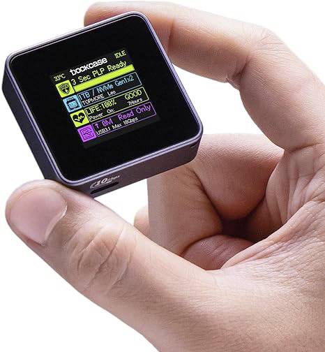 A hand is holding a small rectangular device with a digital display showing information in various colours.