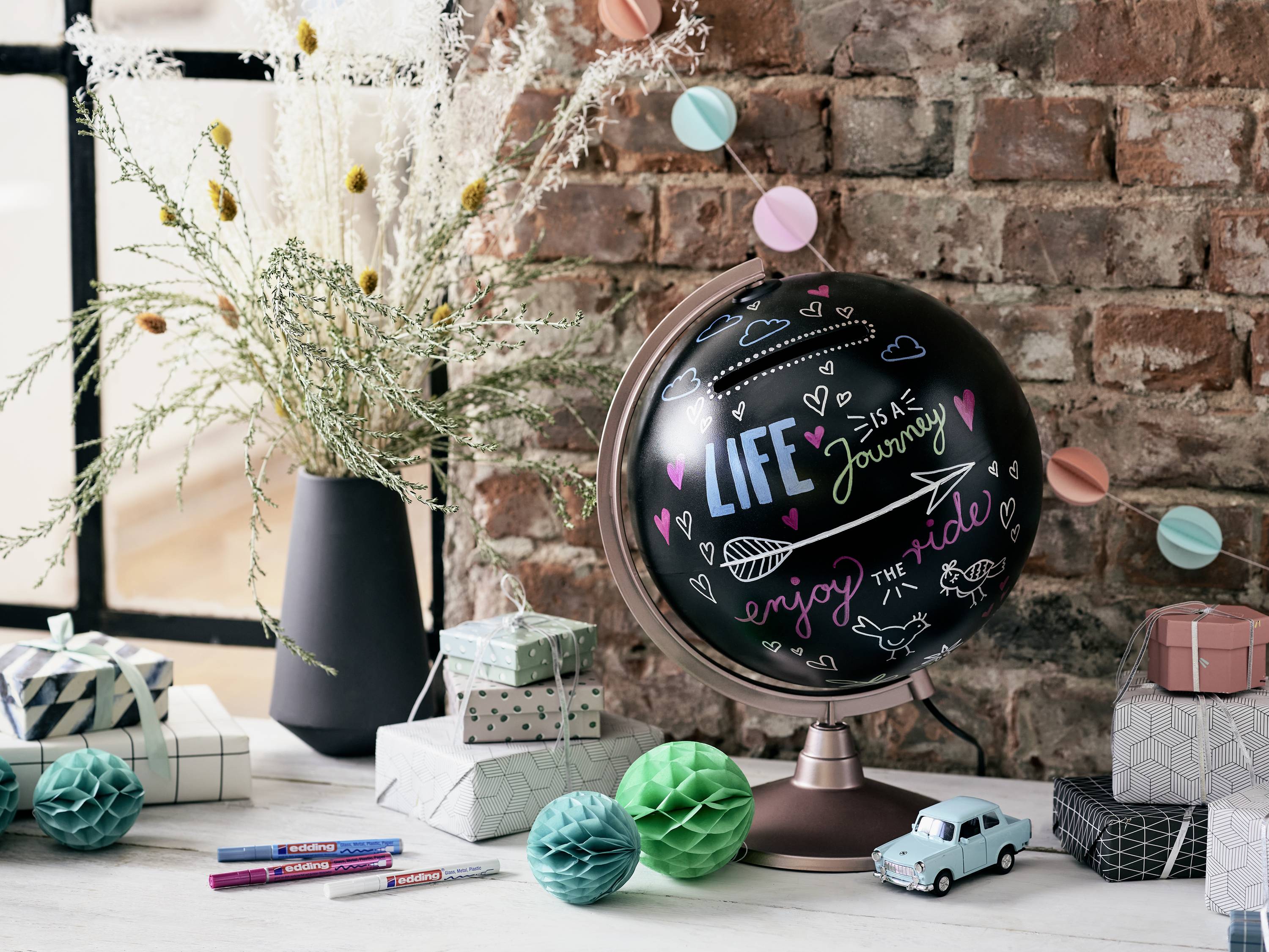 A globe with the inscription 'Life is a Journey, Enjoy the Ride' sits on a table, surrounded by gifts and decorations.
