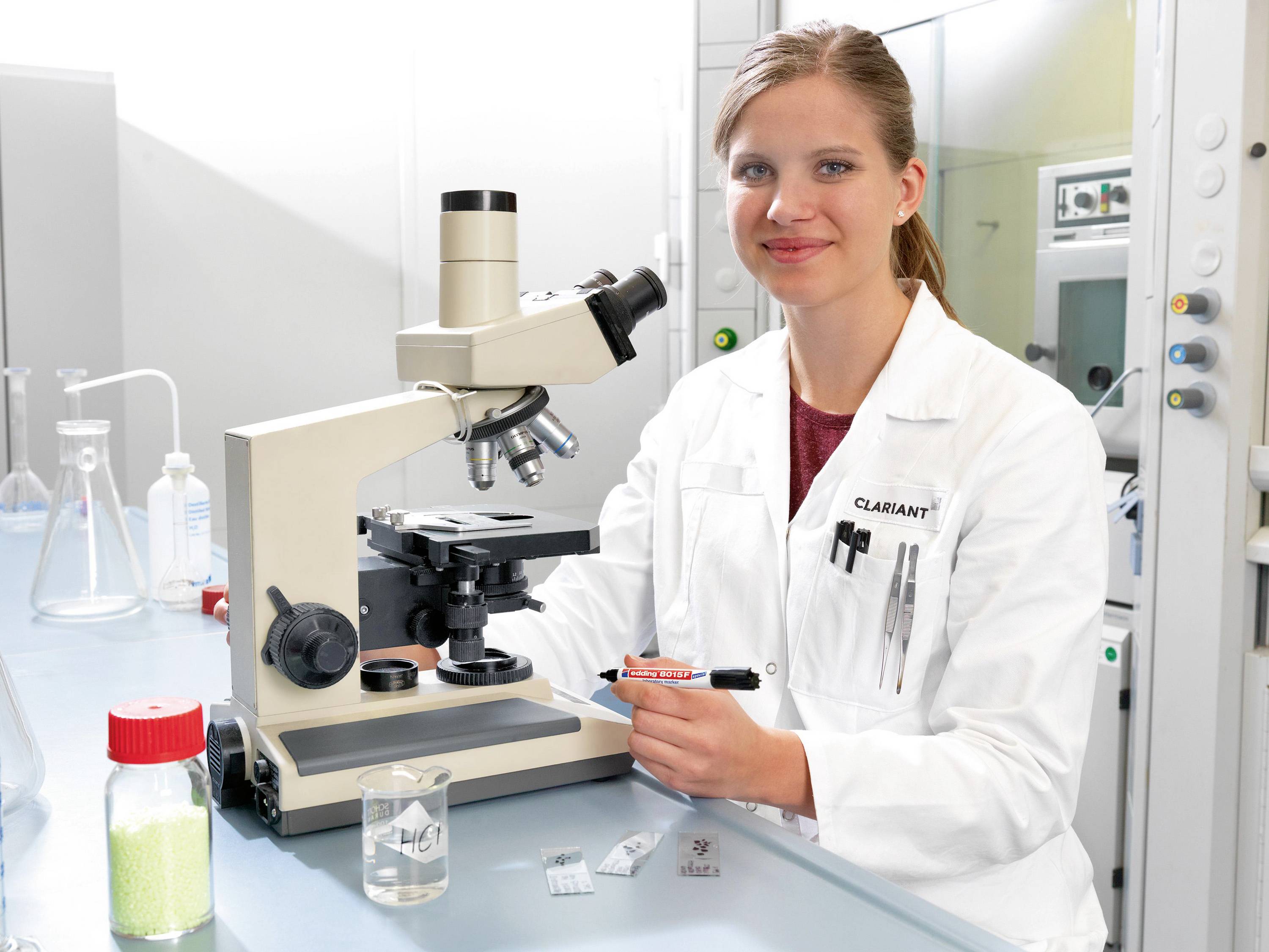 A person in a white lab coat is working with a microscope.