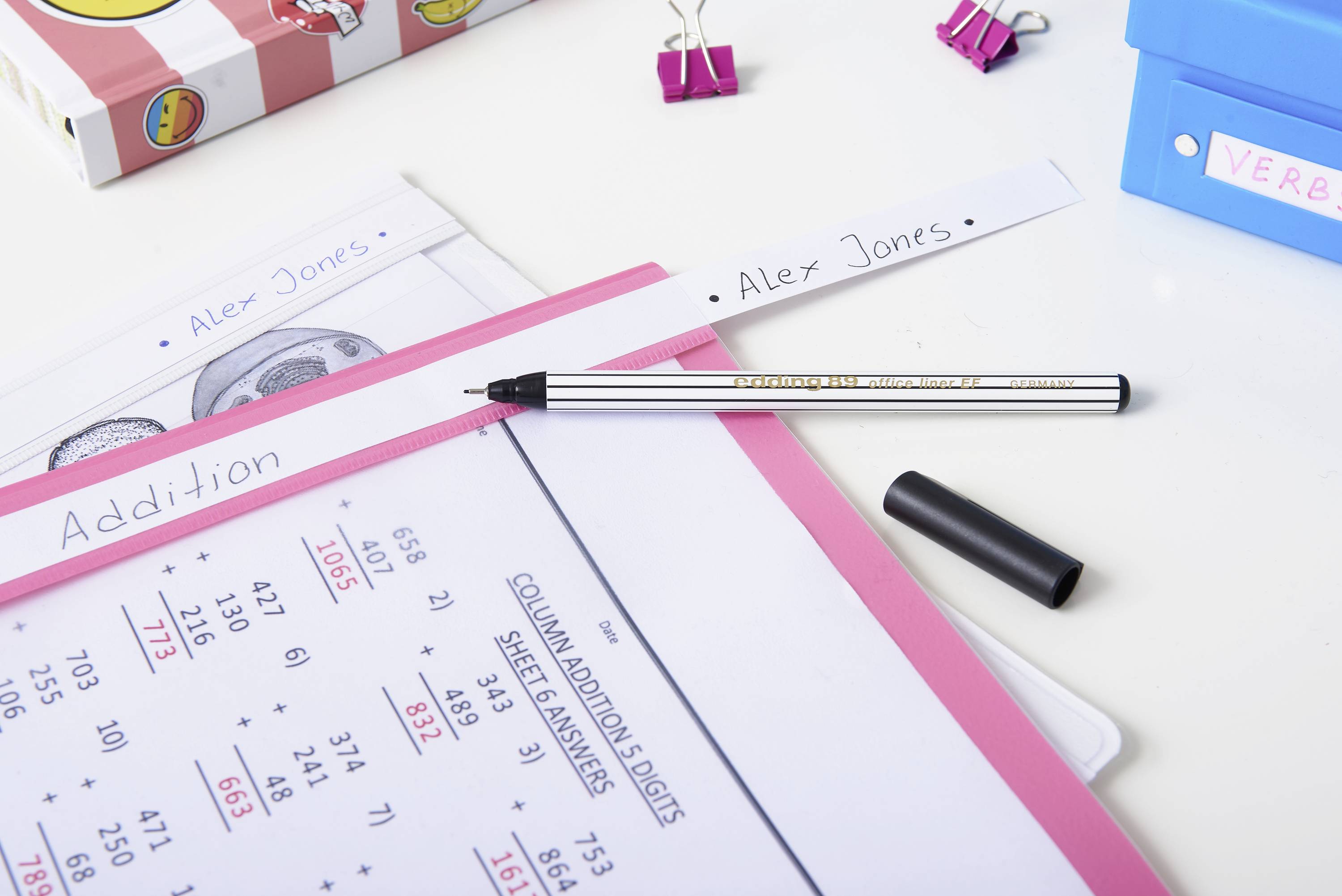 A desk with a worksheet titled 'Addition'. A pen lies beside it, and folders are in the background.