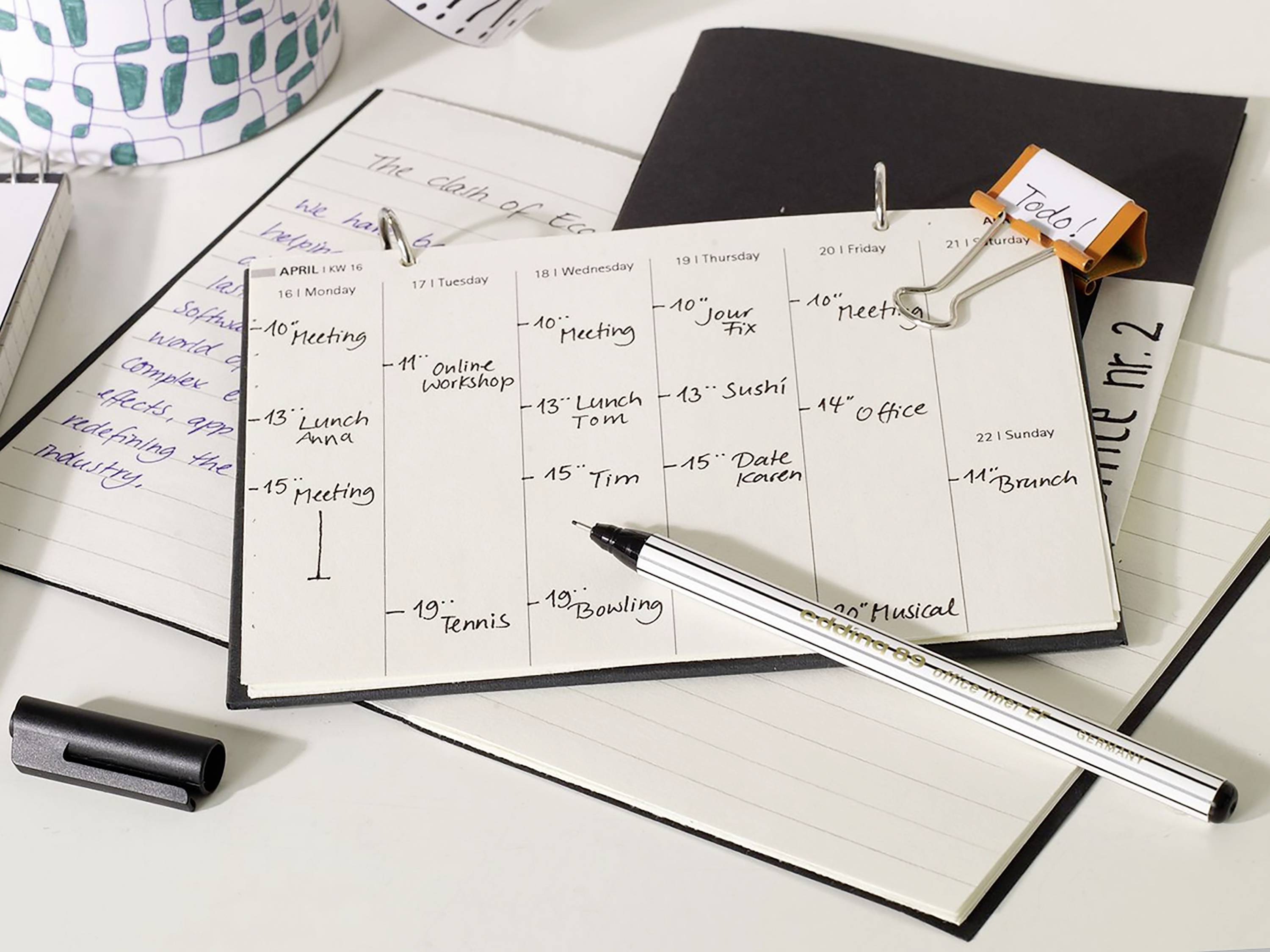 An open calendar lies flat, displaying handwritten appointments for April, including meetings, workshops, and leisure activities such as bowling.