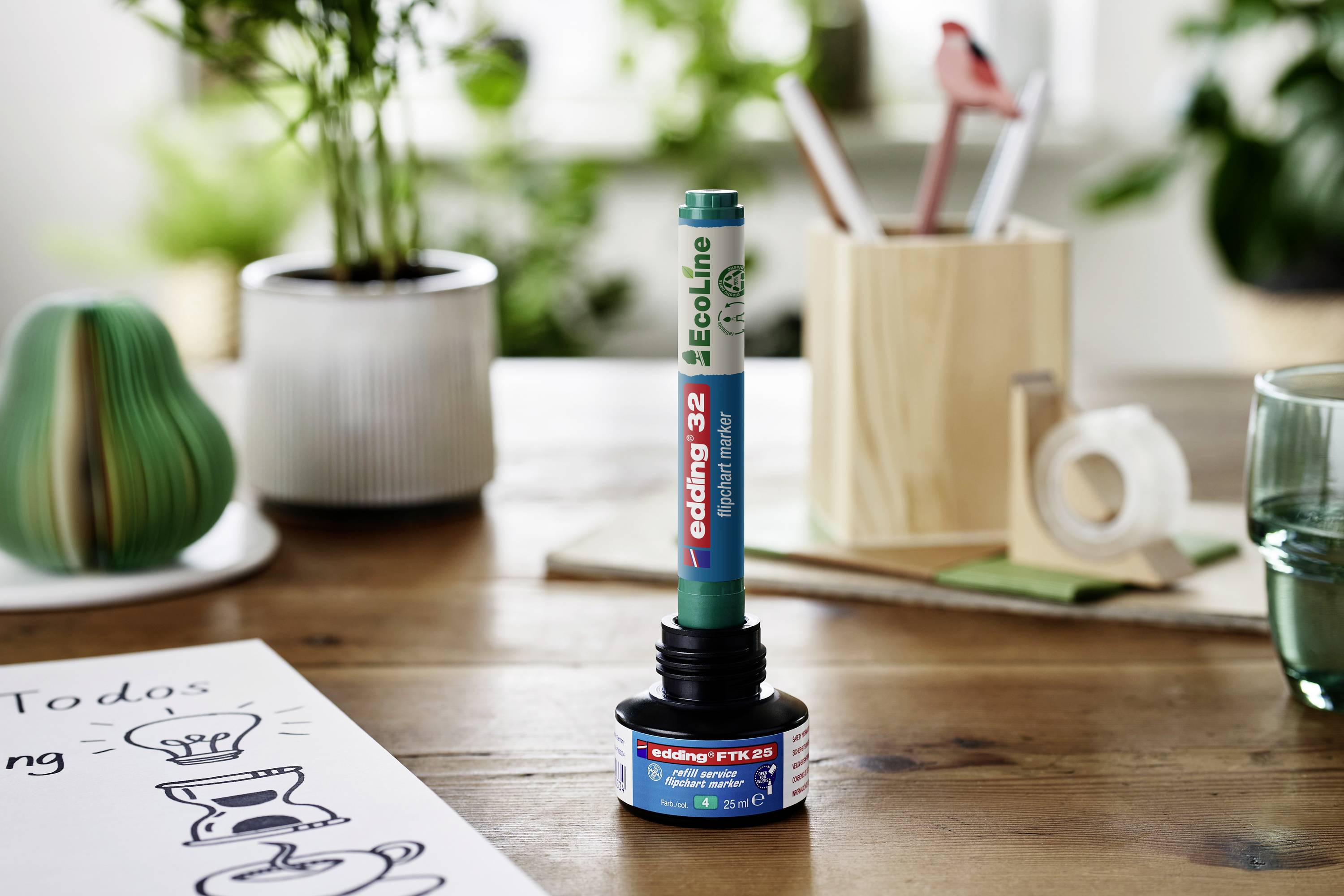 'Recyclable marker with refillable ink on a desk, surrounded by plants and office supplies, promotes sustainability.'