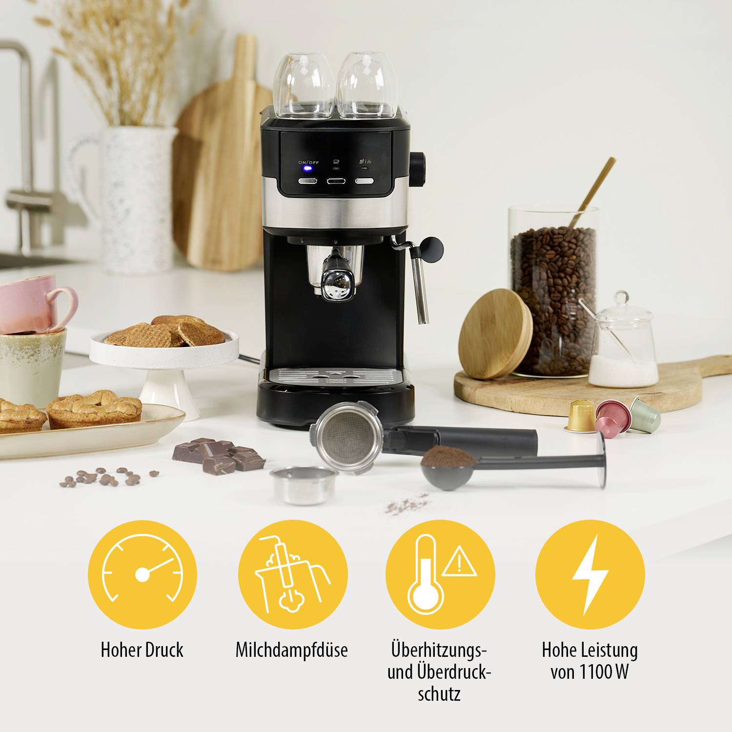 An espresso machine in a kitchen with accessories. Symbols below show functions: 'High Pressure', 'Milk Steam Nozzle', 'Overheating and Overpressure Protection', 'High Power of 1100 W'.