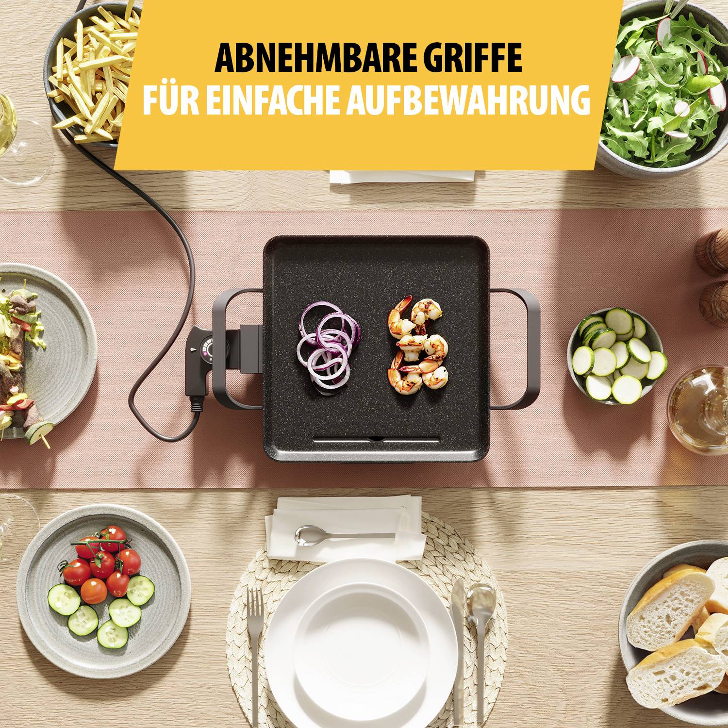 Table with a grill device in the middle, with prawns and onions on it. Surrounded by plates with side dishes. Text at the top: 'Removable handles for easy storage'.