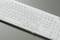 Wet white keyboard with water droplets on a grey background, showing potential water damage susceptibility or splash water protection.