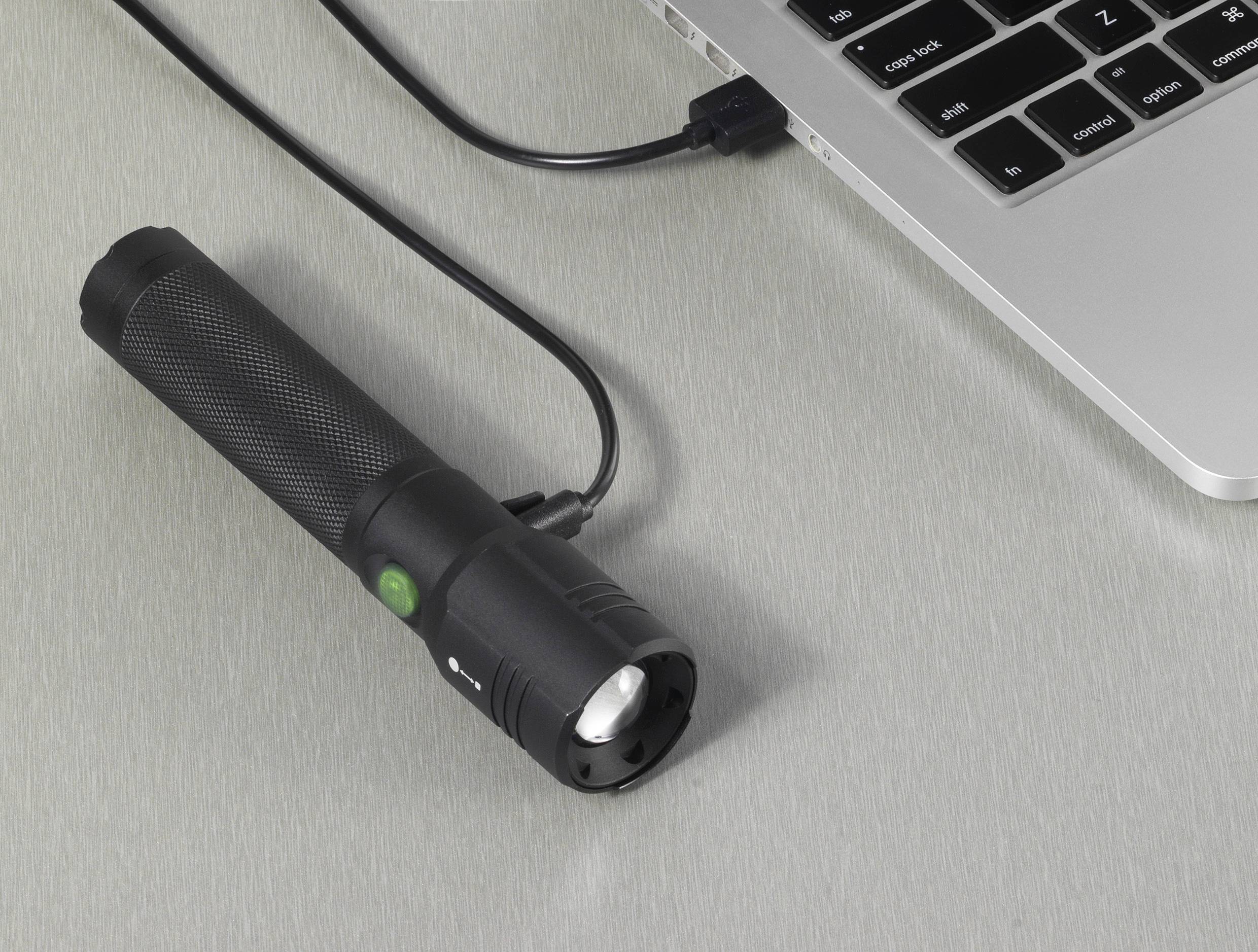 A torch is connected to a laptop via a USB cable. It appears to be lying close to the keyboard.