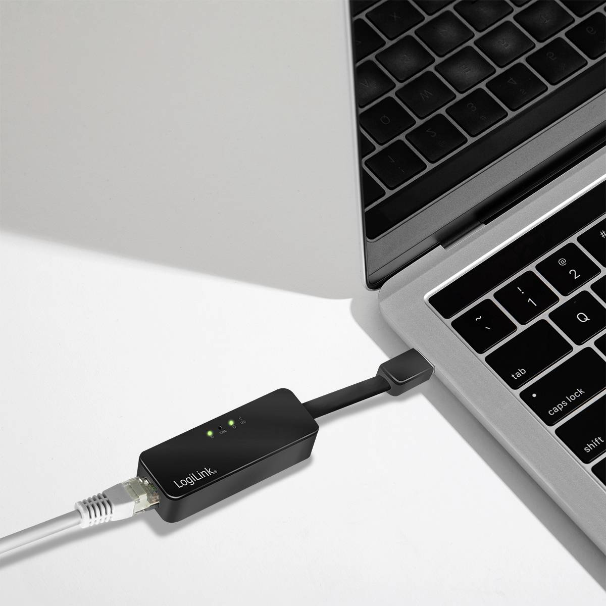 A USB network adapter is connected to a laptop. Three green LED lights indicate the connection status.