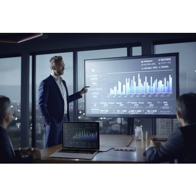 A businessman is presenting a graph on a screen during a meeting in a modern office, with three people listening.