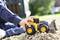 A child is playing outdoors with a yellow toy digger on a gravel bed, focused on the construction vehicle.