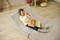 A child is lying on a grey cushion, wearing blue headphones and playing with a wooden toy in a children's bedroom.