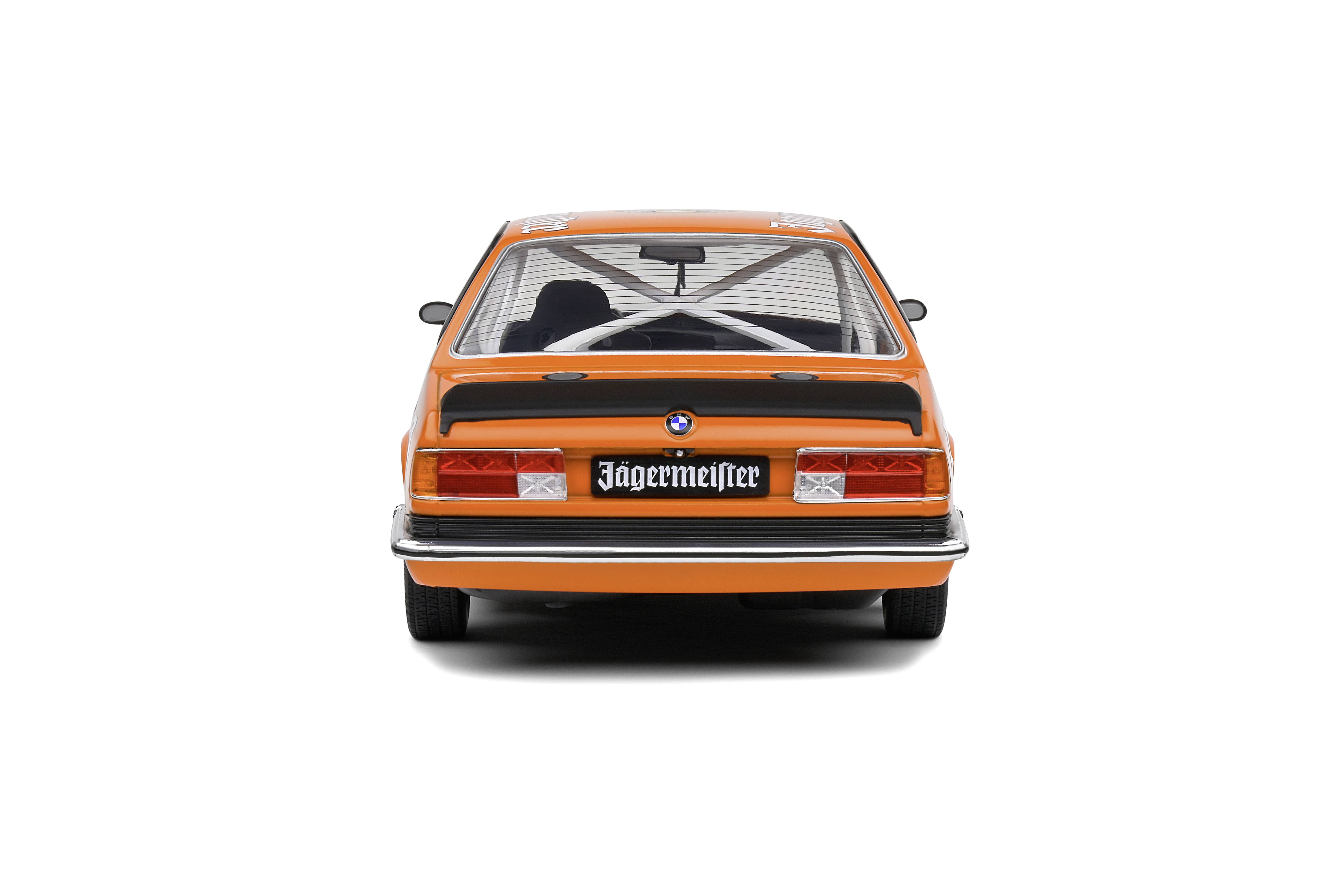 Rear view of an orange racing car with 'Jägermeister' lettering, spoiler and safety cage visible through the rear window.