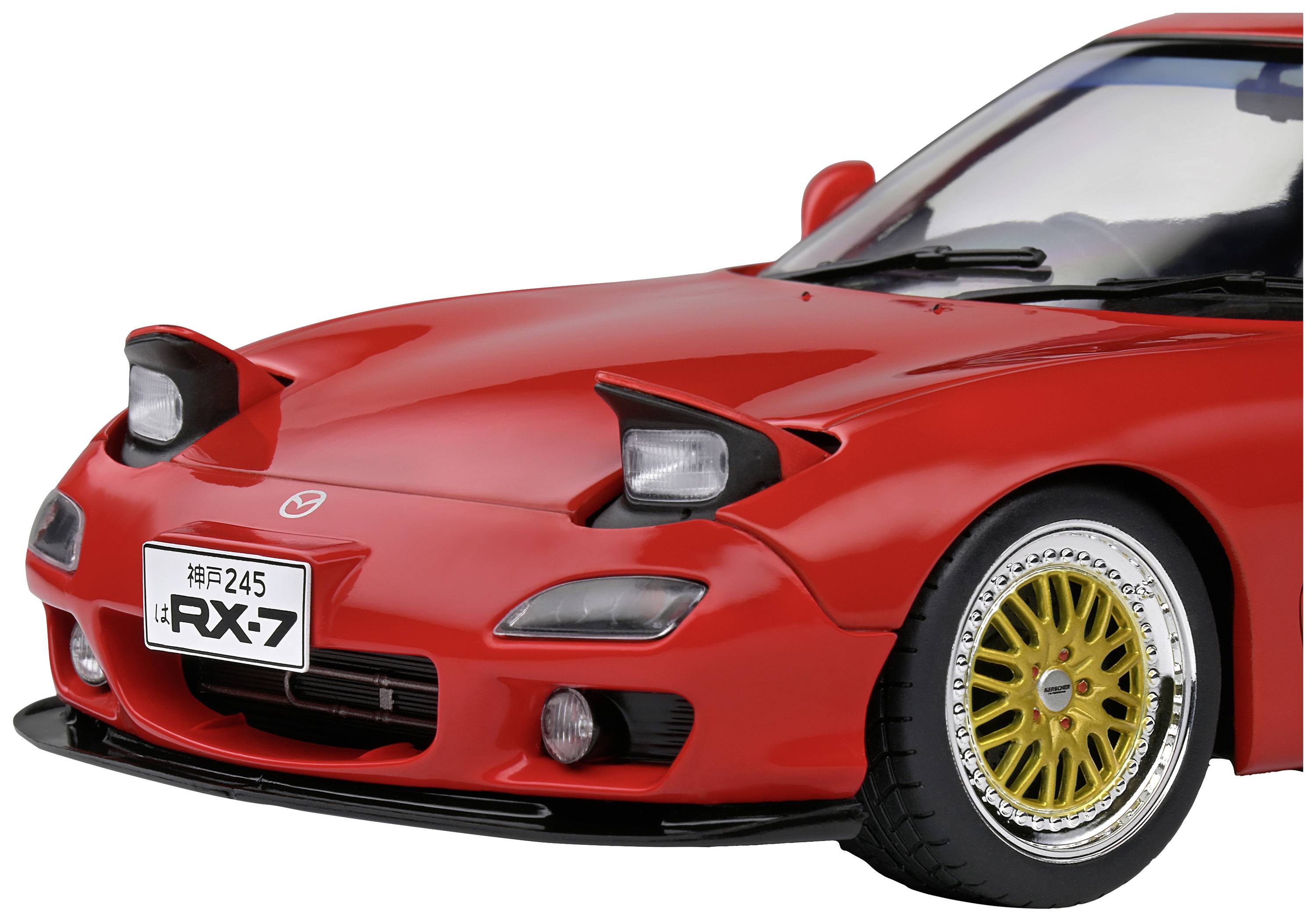 A red sports car with open headlights, golden alloy wheels, and an 'RX-7' number plate, photographed from a front-angled perspective.