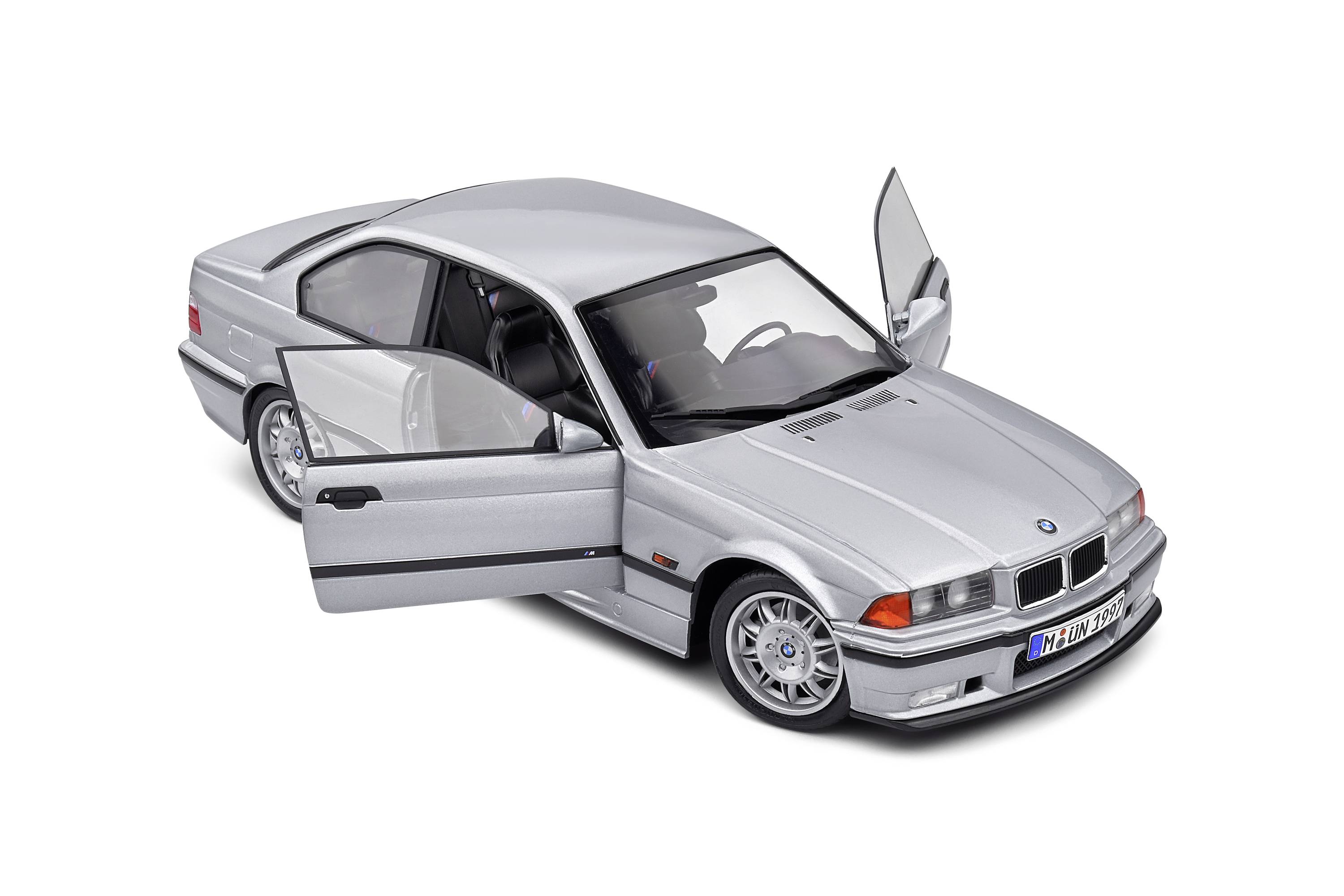 Silver model car with open doors, dark windows, and detailed tyres, positioned on a white surface.