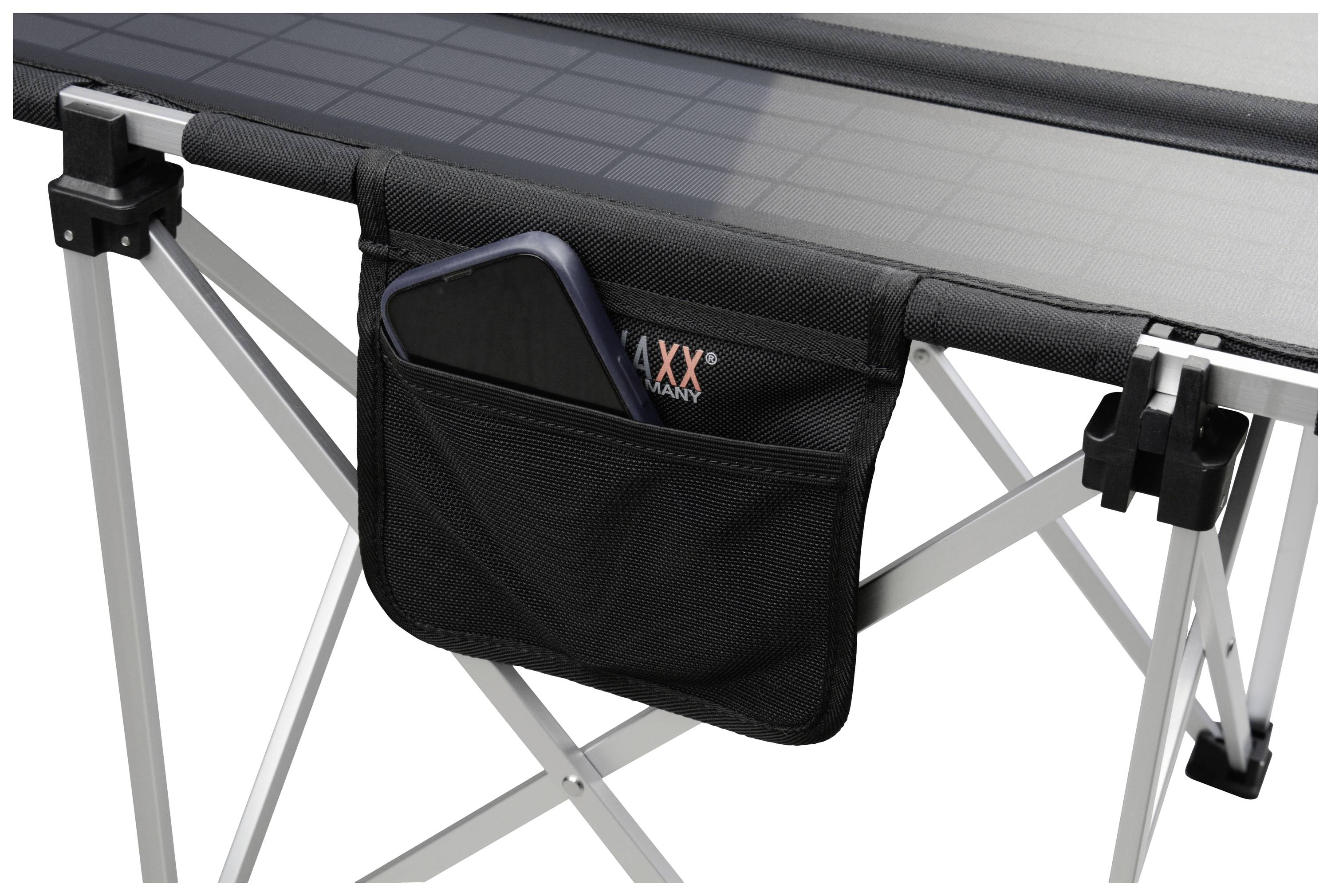 Folding camping table with a black side storage bag containing a smartphone. Metal-framed table legs.