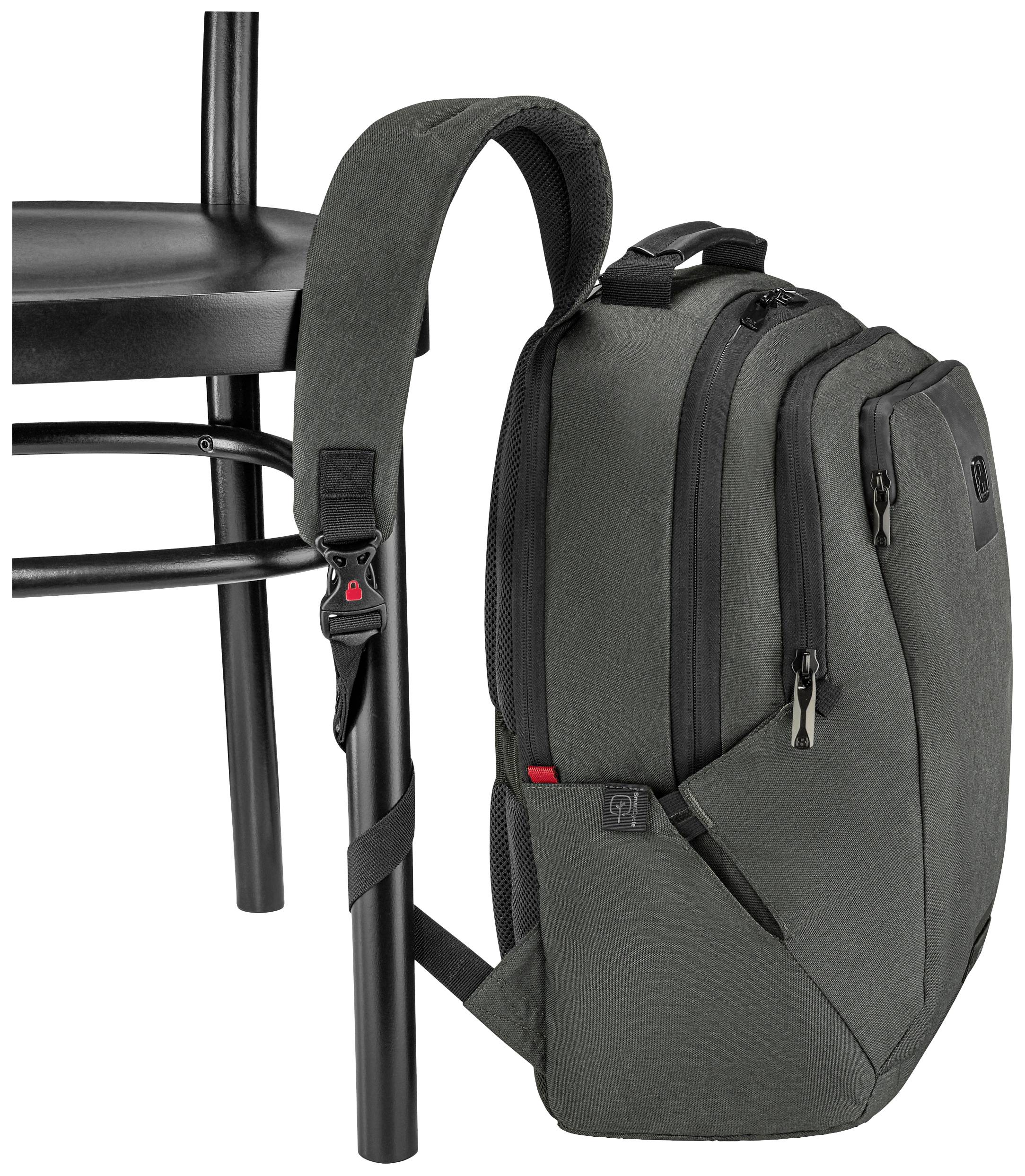 Dark green rucksack hangs on a black chair. The rucksack's strap is fastened around the chair leg.