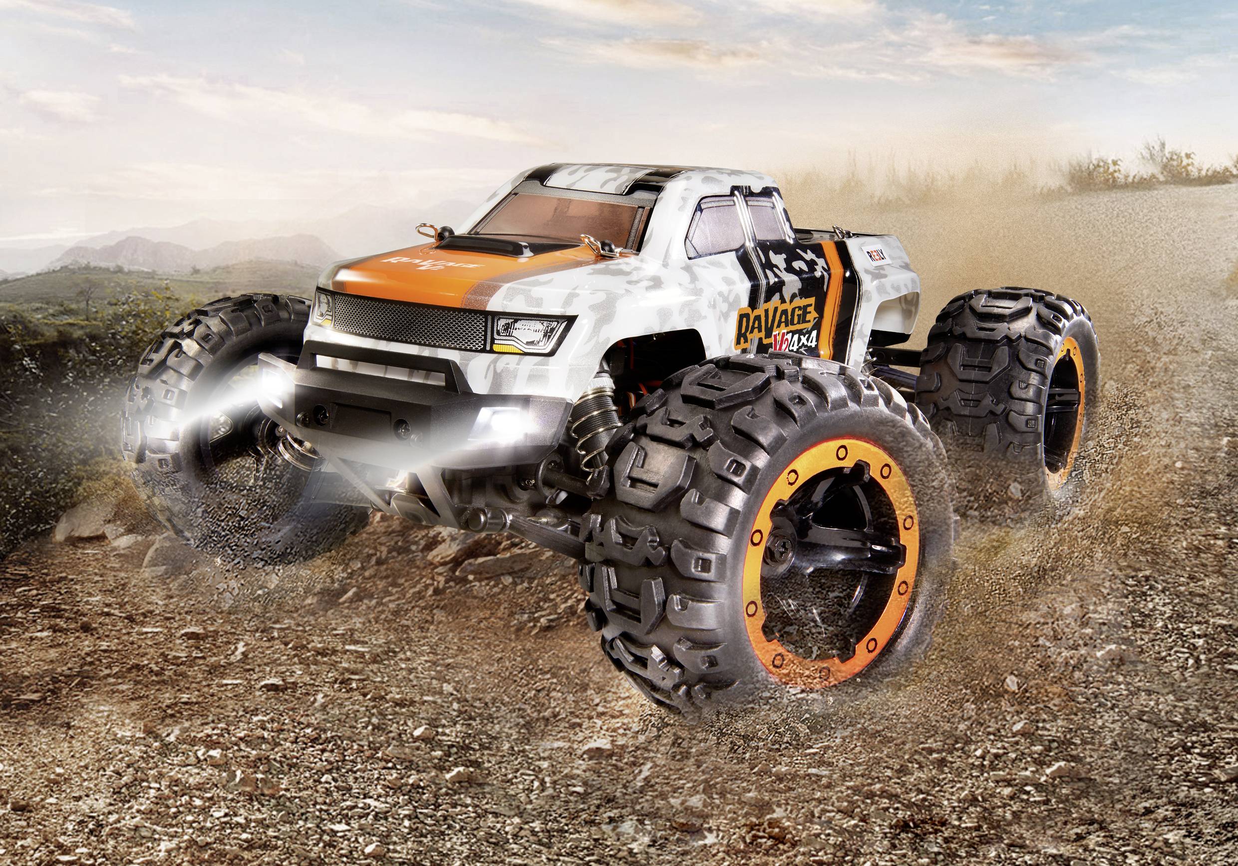 A remote-controlled, robust off-road vehicle drives dynamically along a rocky path. It kicks up dust and conveys a sense of movement and speed.