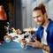 A smiling man is building a model car from Lego. The car is intricately designed with orange and white pieces.