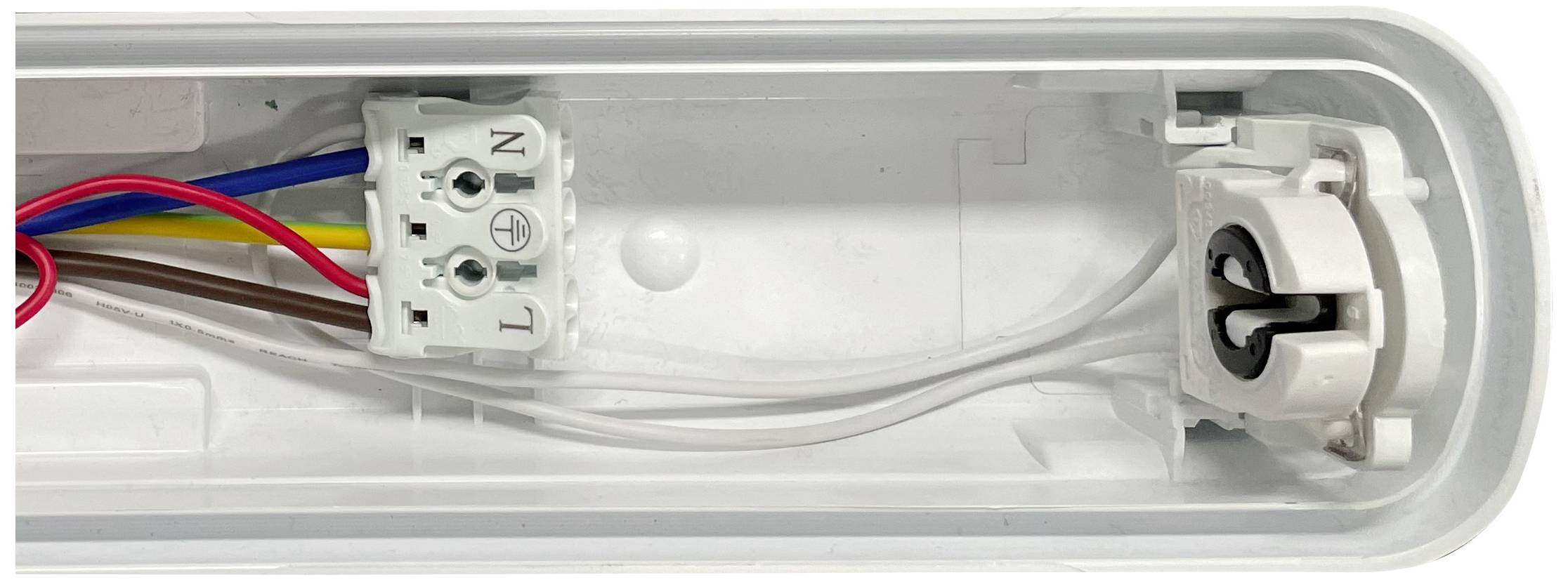 Open casing of a fluorescent lamp with visible cables and connection terminals. On the left, the terminals are labelled with L and N.