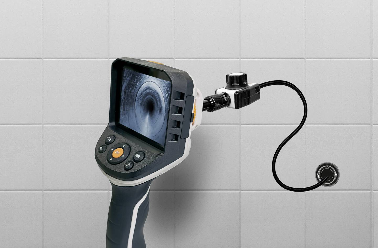 Endoscope camera with a flexible swan-neck reveals the screen content of a dark tube. Grey tiles in the background.