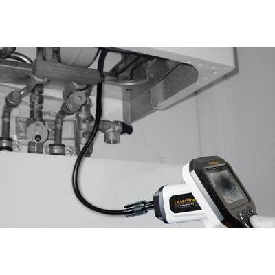 A plumber inspects the pipes of a boiler with an endoscope to check for leaks or damage.