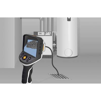 A thermal imaging camera displays a heating system with irregular temperature patterns on a digital display. Heating pipes are visible in the background.