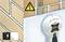 A wall detector shows the position of electrical cables behind a wall. A warning sign indicates electrical danger.