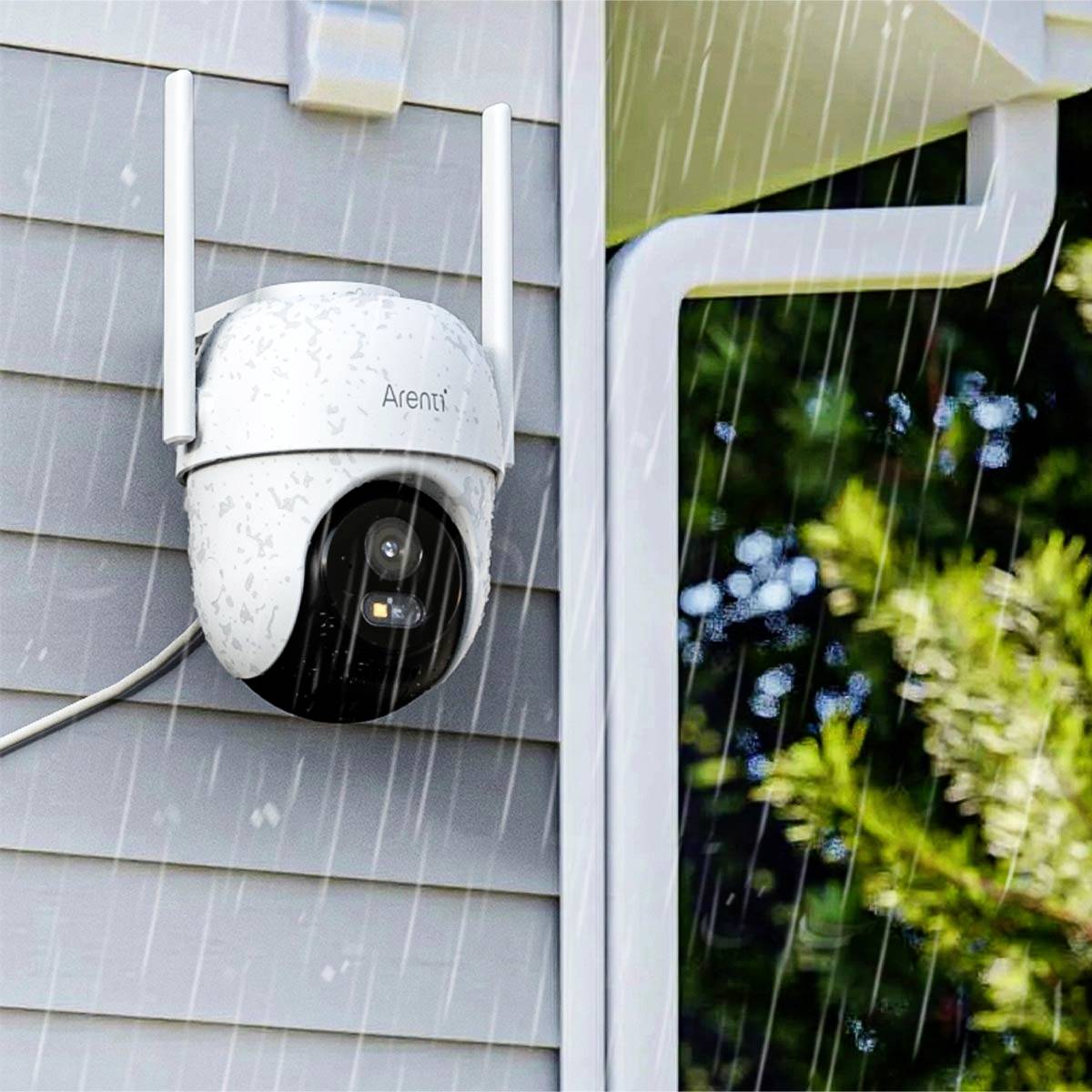 A surveillance camera is mounted on a house facade. It is raining, and the camera is weatherproof.