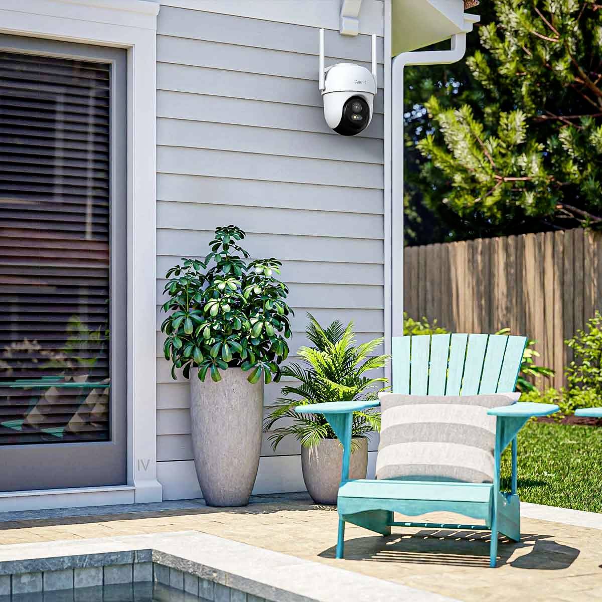 A modern outdoor area with a security camera mounted on the wall, a blue chair with a cushion and two potted plants.