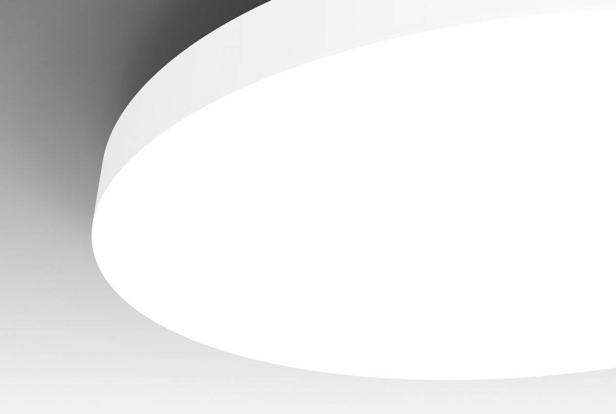 Large white ceiling light illuminates a modern room. The round shape is smooth and simple, surrounded by grey shadows.