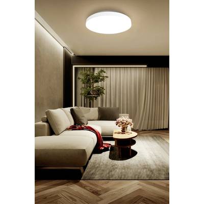 A stylishly decorated living room with a large, beige corner sofa, a round wooden table and a rug on a wooden floor.