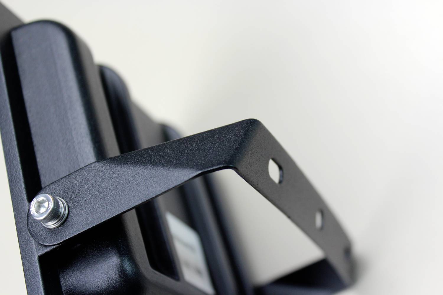 Metal mounting bracket with a screw on a black device. Background blurred. Focus on the simple construction and texture of the metal.