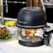 Kitchen appliance on worktop with roast chicken cooking, exposed, with a bowl of lemons and fresh herbs beside it.