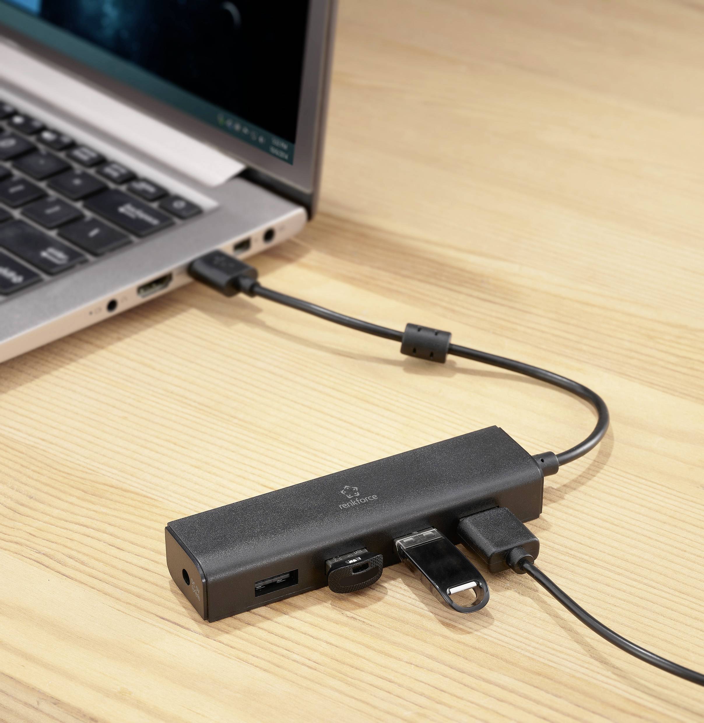 A laptop is connected to a black USB hub, which provides multiple ports for additional devices.