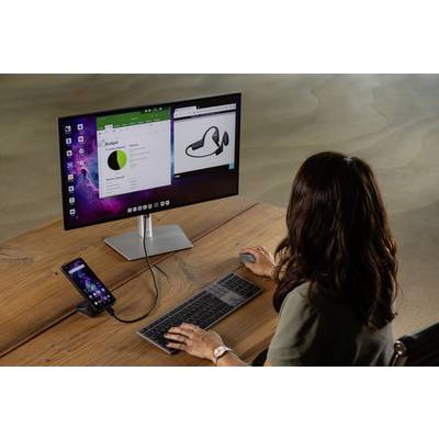A person is working at a monitor with a keyboard and mouse. A smartphone is connected to the monitor and displays an extended view.