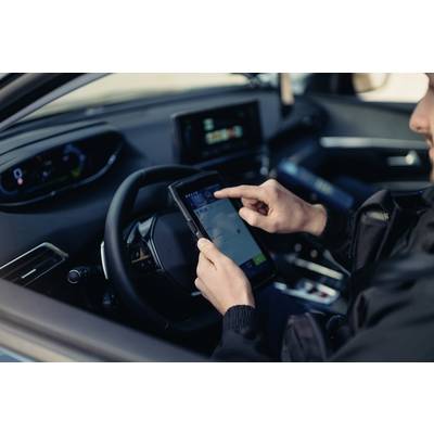 A person is using a tablet for navigation in a car. The screen displays a map view, with the steering wheel and car interior in the foreground.