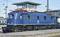 Blue electric locomotive of Deutsche Bahn stands on a railway track. In the background, a signal box is located.