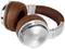 Brown and silver over-ear headphones made of metal and leather are positioned at an angle to each other on a white surface.