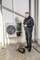 A technician is repairing an air conditioning unit outside. He is holding a tool and standing next to an opened device with cables.