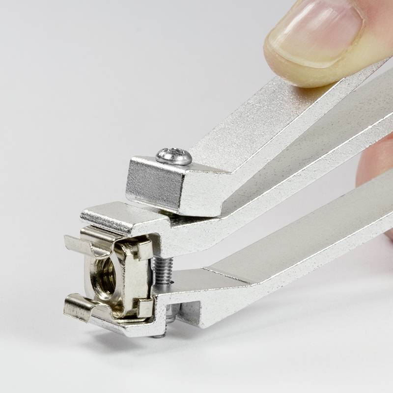 A hand is holding a silver multi-functional tool, possibly a clamp or fixing device.