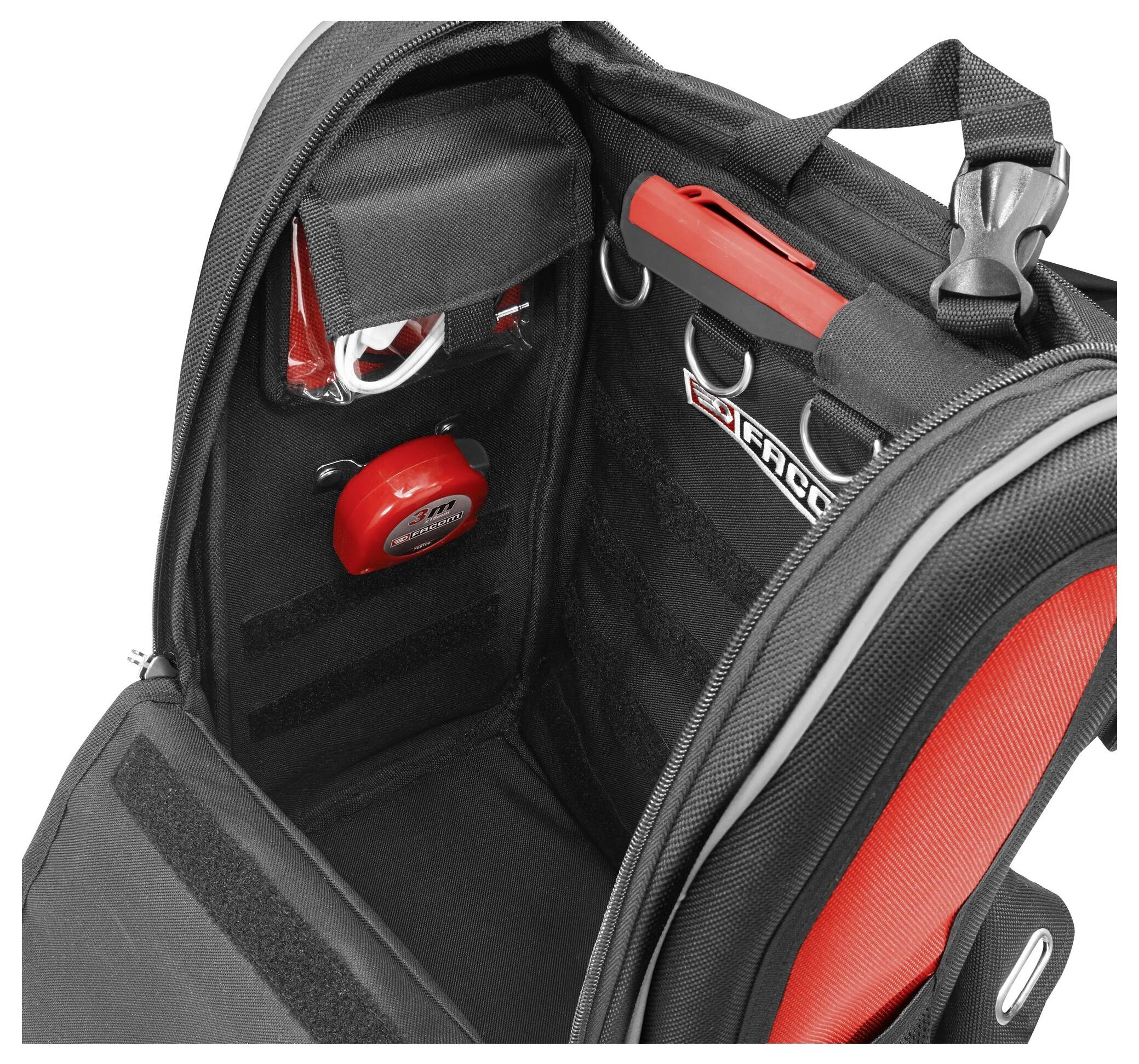An open rucksack compartment with red and black elements. Visible are a red button, straps, and a clear pocket.