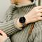 The person is wearing a grey jumper and a black wristwatch with a digital display.