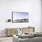 A living room with a sofa, a wooden TV cabinet and a flat-screen television mounted on the wall, displaying a landscape.